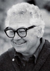 Portrait of James Peter Cost, smiling, in thick-rimmed glasses