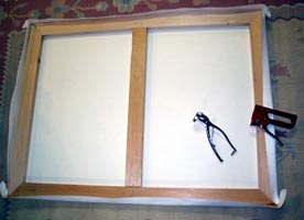 A blank canvas stretched on heavy stretcher bars, with stretching pliers