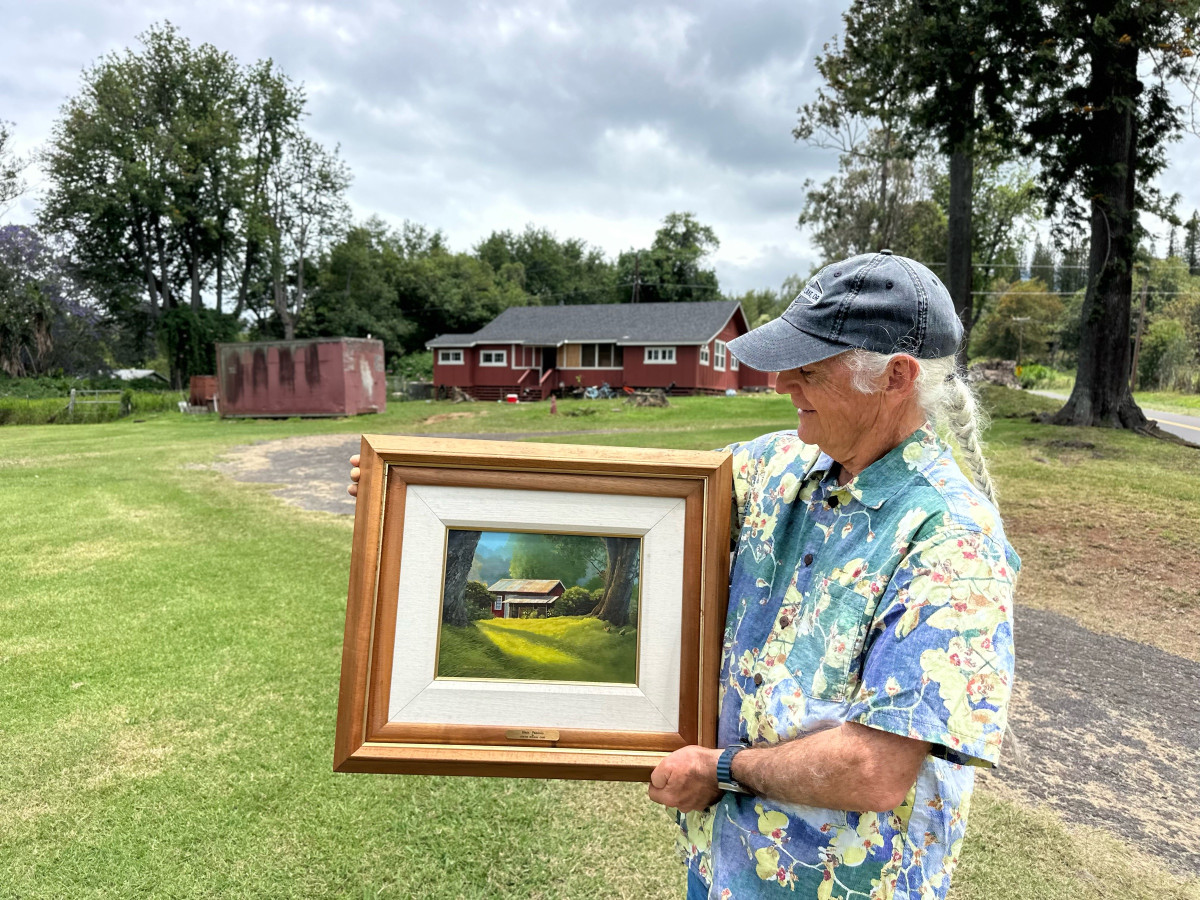 The red house in the old dairy area of Makawao, with a painting of it held up in front