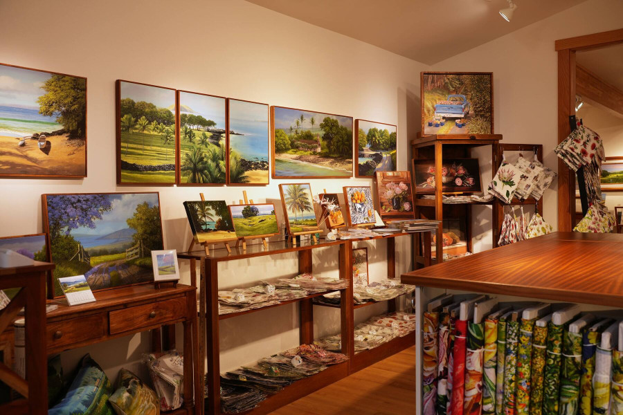 Paintings on the walls above shelves of cards, prints and fabrics
